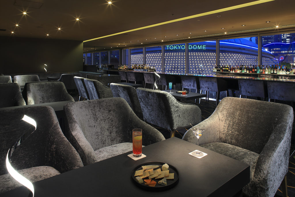 Elegant lounge seating area at Bar 2000 Tokyo Dome Hotel with cocktails and Tokyo Dome illumination backdrop