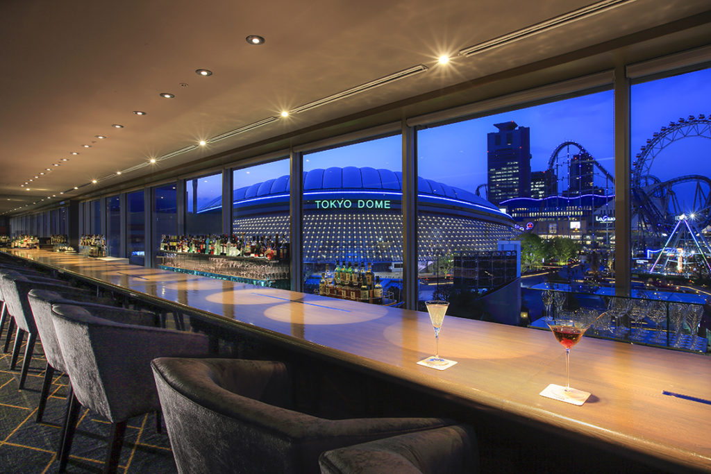 Bar 2000 long counter at Tokyo Dome Hotel with panoramic Tokyo Dome City illumination view during evening hours